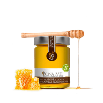 Bote de 900 gramos de miel de azahar ecológica de Bona Mel con un trozo de colmena y un palo de madera de panal sobre fondo transparente